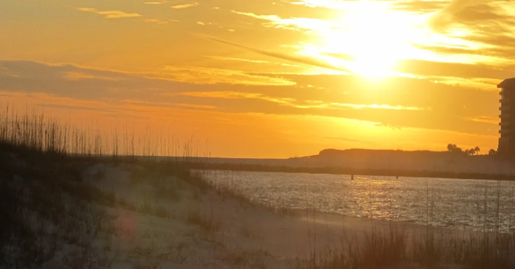 Golden sunset over dunes and water at Orange Beach, Alabama