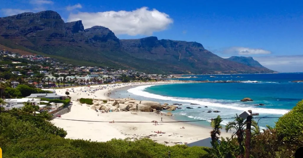 A picturesque African beach with turquoise waters, golden sands, and lush greenery under a bright blue sky.